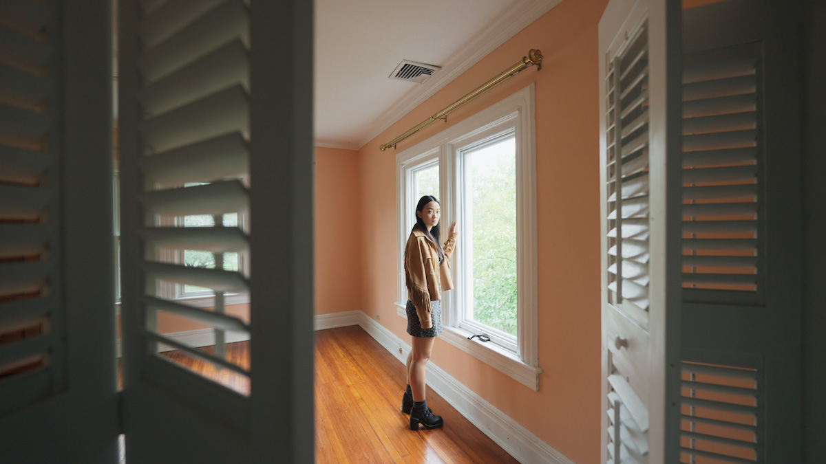 Chloe (Callina Liang) se tient devant la fenêtre de sa chambre, elle regarde droit vers la caméra placée dans son placard