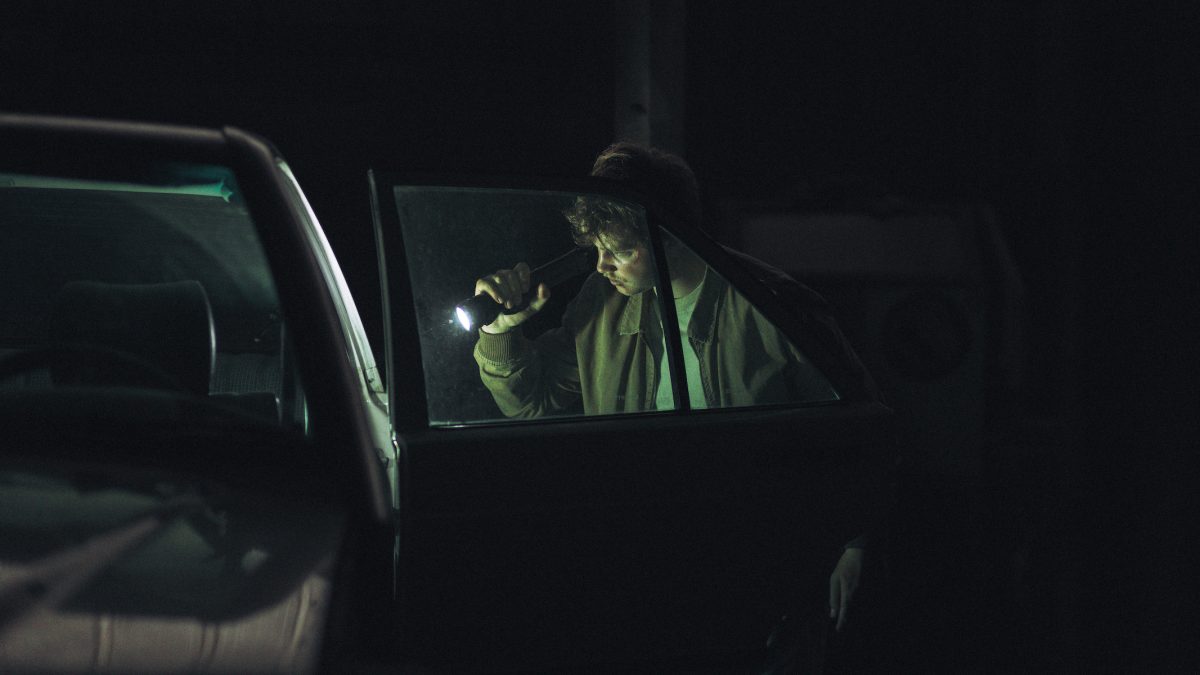 De nuit, Paul Chartier inspecte une voiture à la lumière de sa lampe torche