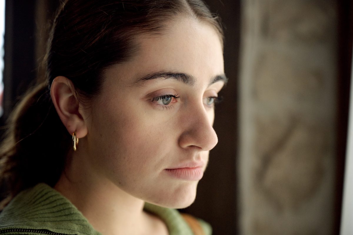 Image très rapprochée sur le visage de Sam qui est visiblement touchée et attristée. Elle regarde dans le vide.