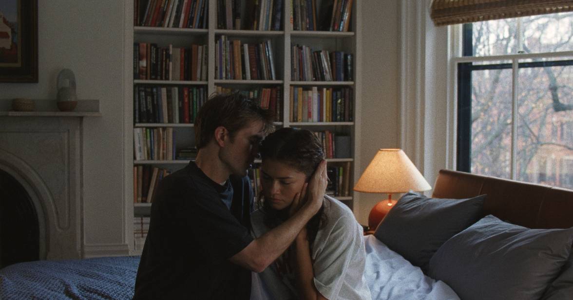 Image issue de The Drama. Emma et Charlie sont assis sur le lit situé dans leur chambre. Charlie chuchote quelque chose dans l'oreille sourde de cette dernière pendant qu'elle se bouche son oreille encore fonctionnelle. 